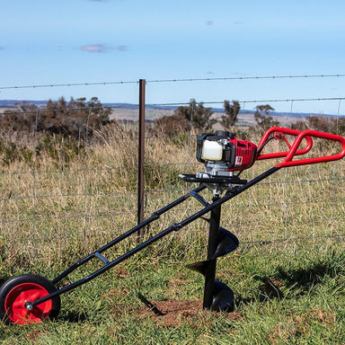 Bullmax BMEAW-H50W one-man wheeled earth auger powered by Honda GX50 engine in active use. Shown drilling a fence post hole in a grassy paddock. Features ergonomic handles, robust auger bit, and large wheel for effortless maneuverability on uneven terrain.