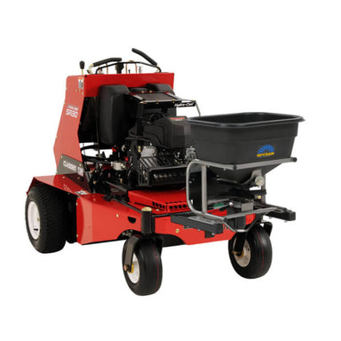 Close-up view of the front-mounted broadcast spreader attached to the Classen SA30 stand-on aerator. The black spreader hopper is supported by a sturdy metal frame and includes a directional control plate, designed for efficient lawn material distribution.