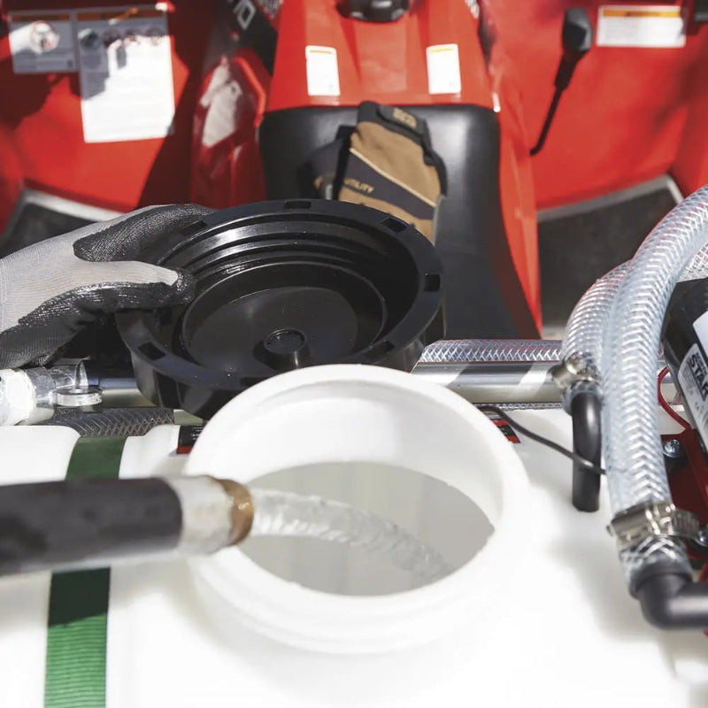 Close-up of a NorthStar 12V ATV sprayer being refilled with water through a wide tank opening, showing hose connection and screw-on black lid for secure sealing.