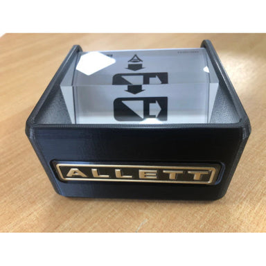 Allett Grass Gauge prism tool for measuring lawn height. Transparent optical prism with engraved height markings and a black base featuring the Allett logo, designed for precise turf and grass maintenance measurement.