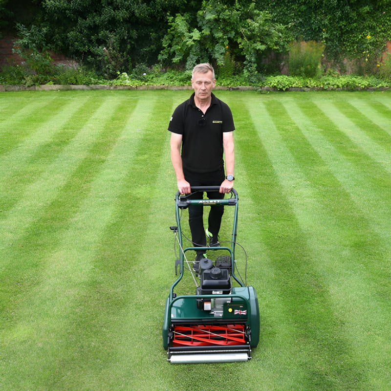 Operator using the Allett Kensington 20H petrol cylinder mower to create clean lawn stripes with a precision rear roller and powerful engine.
