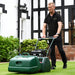 Man mowing a lawn with the Allett Kensington 20H petrol cylinder mower, featuring a rear roller and grass catcher for a professional striped finish.