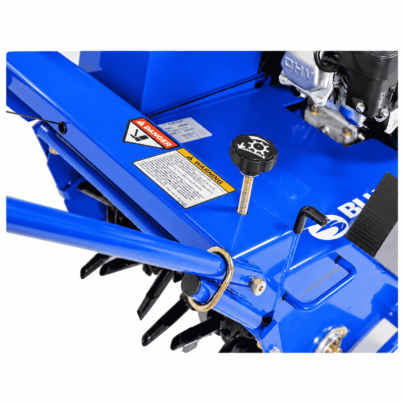 Crommelin 530HP Bluebird Lawn Aerator 19 close-up showing the adjustable depth control knob, blue steel housing, safety labels, handle mounting hardware and visible coring tines.