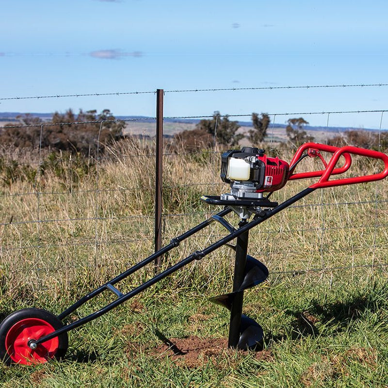 Bullmax BMEAW-H50W one-man wheeled earth auger powered by Honda GX50 engine in active use. Shown drilling a fence post hole in a grassy paddock. Features ergonomic handles, robust auger bit, and large wheel for effortless maneuverability on uneven terrain.