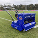 Side view of the Campey Turf Care Pedestrian AeraSeeder by Reist Industries in action on a sports field, featuring a Honda GX engine, spiked rollers for overseeding, and durable blue frame, designed for precise seeding and turf care maintenance.