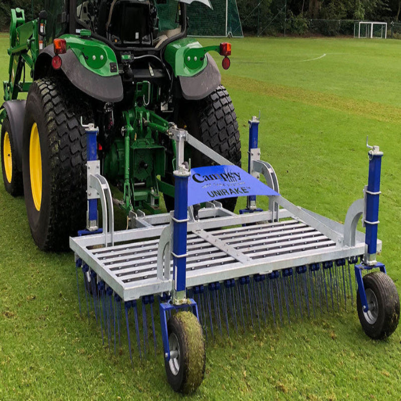 Rear view of a tractor towing the Campey UniRake on a grass sports field. The UniRake’s spring tines are designed for turf maintenance, helping to relieve compaction, improve aeration, and enhance pitch quality for football, rugby, and natural grass surfaces.