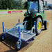 Rear view of a tractor towing the Campey UniRake across a soil-based sports field. The UniRake’s spring tines aerate and prepare the ground, improving seedbed conditions, drainage, and turf quality. Ideal for maintaining natural grass pitches and fine turf surfaces.