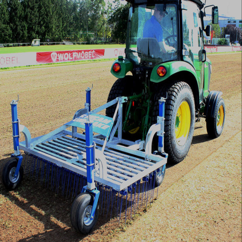 Rear view of a tractor towing the Campey UniRake across a soil-based sports field. The UniRake’s spring tines aerate and prepare the ground, improving seedbed conditions, drainage, and turf quality. Ideal for maintaining natural grass pitches and fine turf surfaces.