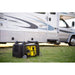 Champion 4500-watt inverter generator operating beside a parked RV on grassy ground. The portable yellow and black generator is plugged in, demonstrating quiet, efficient power for camping or outdoor travel applications.