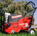 Side view of the Classen TA22H PRO Steerable Aerator on green grass, showcasing its red frame, compact design, control handle, black engine housing, and front caster wheel. Prominent Classen and TA22 labels highlight its identity as a turf aeration machine.
