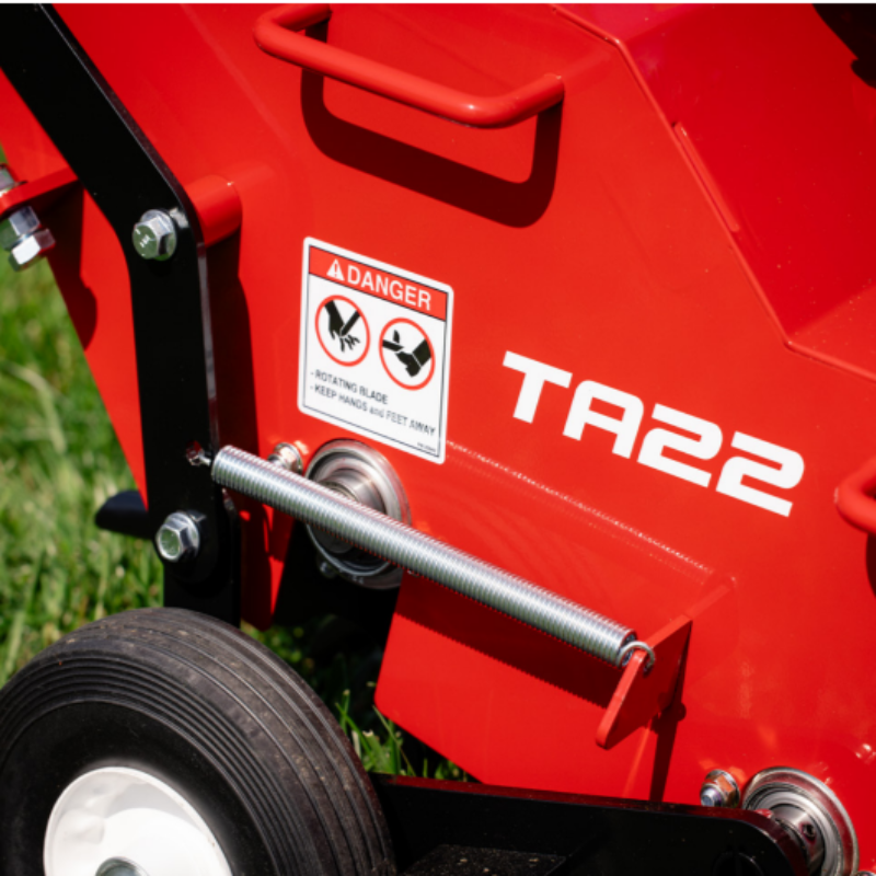 Close-up of a Classen TA22H aerator showing the warning label, wheel assembly, and part of the chassis, with a visible danger sign cautioning about rotating blades and instructing to keep hands and feet away