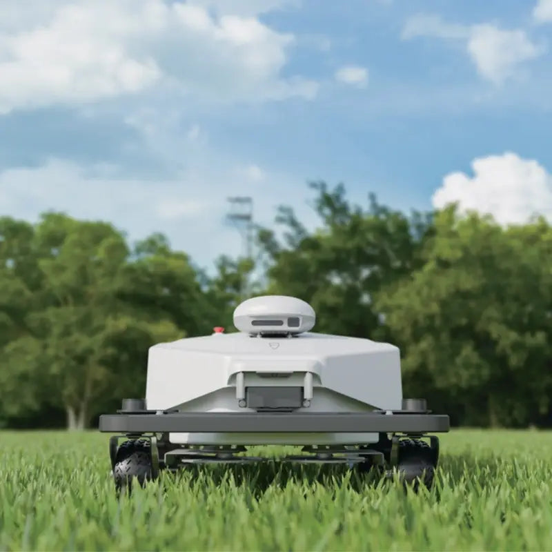 Front view of the FJD FRX Robotic Lawn Mower operating on grass, showcasing the RTK positioning module, front safety bumper, floating cutting deck, and autonomous commercial mowing system.