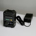 FlowZone 18V 5.2Ah rechargeable lithium-ion battery pack with LED charge indicator lights, shown with black charging adapter and cable, placed on a white surface with a neutral background, designed for powering FlowZone Monsoon 2.5 sprayers.