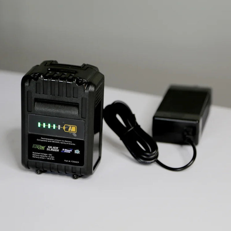 FlowZone 18V 5.2Ah rechargeable lithium-ion battery pack with LED charge indicator lights, shown with black charging adapter and cable, placed on a white surface with a neutral background, designed for powering FlowZone Monsoon 2.5 sprayers.