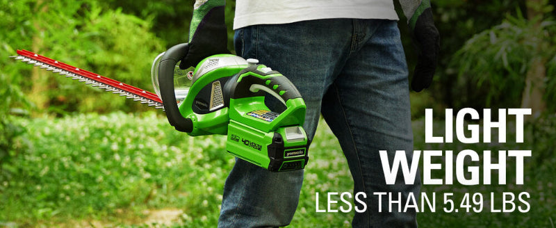Person holding a Greenworks 40V Hedge Trimmer beside their leg in a garden, showing its compact green and black design with red blades. Text overlay reads “Light Weight Less Than 5.49 lbs,” emphasizing portability and ergonomic handling outdoors.