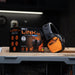 ISOtunes Link 2.0 Bluetooth hearing protection earmuffs shown beside retail box on a workshop bench, featuring over-ear noise reduction and wireless audio, designed for use in loud work environments such as construction, fabrication, and machinery operation.