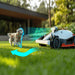 Mammotion Luba AWD X robotic mower on grass detects a small running dog with sensor visualization. Blue digital waves show obstacle recognition, redirecting mower’s path safely, with a modern house and greenery in the background.