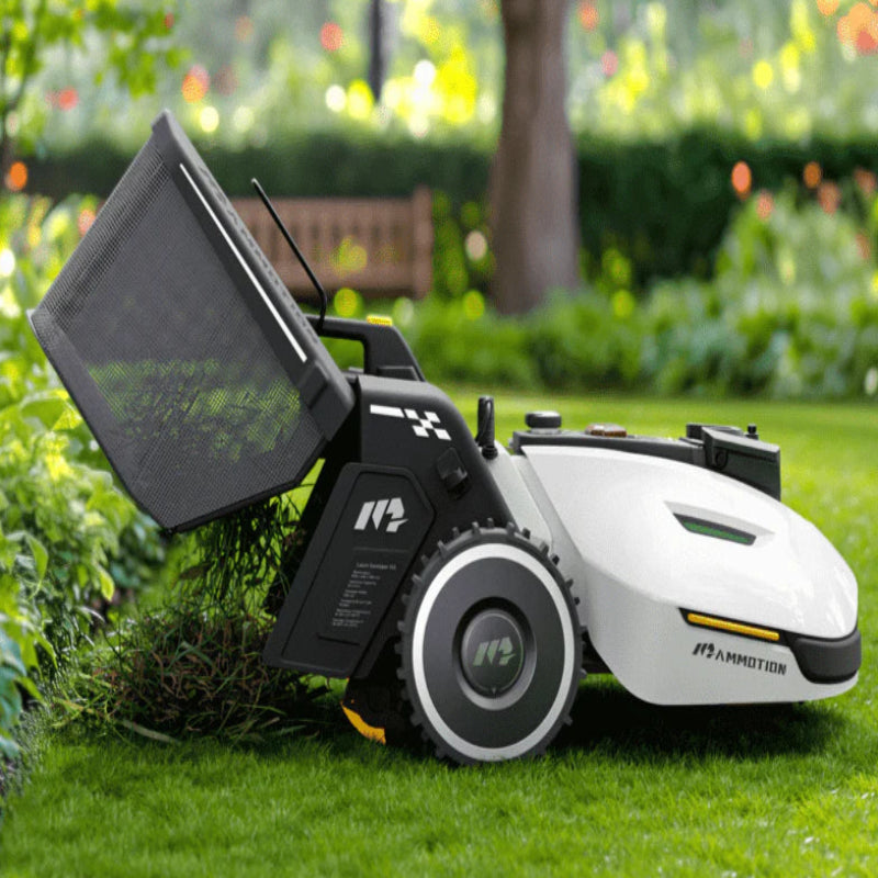 Mammotion Yuka robotic mower with attached lawn sweeper kit shown collecting clippings on a lush green lawn, surrounded by bushes and flowers in a landscaped garden.
