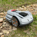 Moebot Acre Eater robotic lawn mower navigating over rocky and uneven ground, showing its durable wheels and all-terrain performance design.