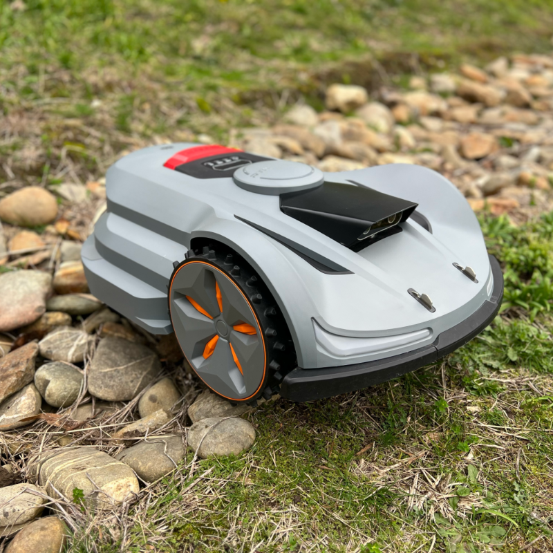 Moebot Acre Eater robotic lawn mower navigating over rocky and uneven ground, showing its durable wheels and all-terrain performance design.