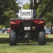 NorthStar 12V ATV sprayer mounted on a red Polaris quad bike, shown from the rear on green grass. The durable tank and hose system are ready for spraying applications in lawns, gardens, or agricultural settings.