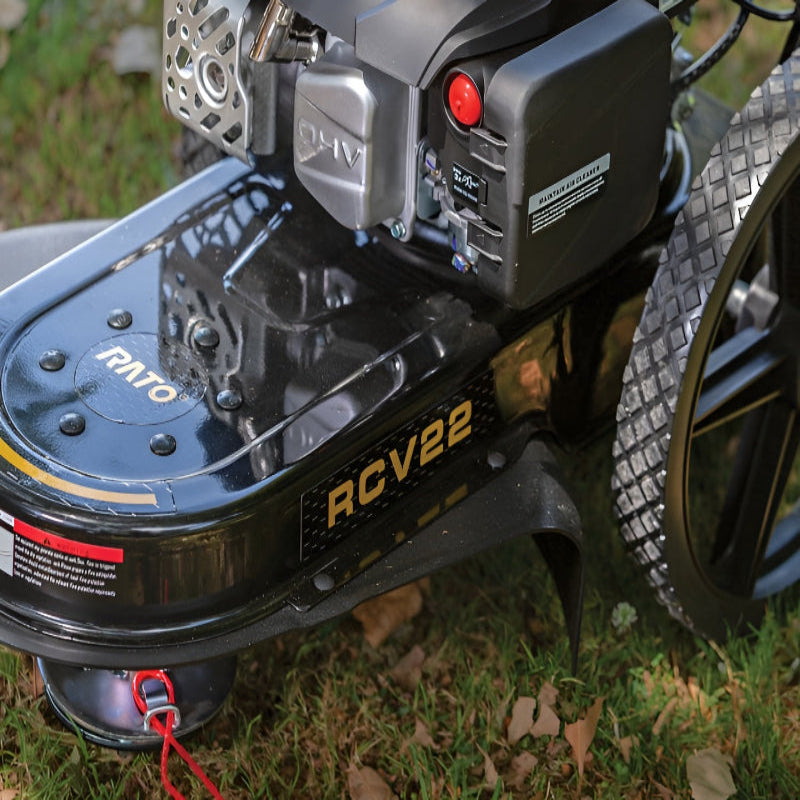 Close-up of Rato RCV22 high wheel trimmer showing heavy-duty steel deck, OHV engine, air filter, and wide tread wheels. Branding clearly visible with RCV22 logo. Designed for trimming tall grass, weeds, and rough vegetation with durable performance.